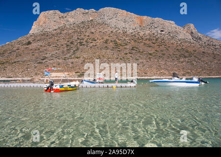 Stavros, Chania, Kreta, Griechenland. Blick über das seichte Wasser der Trahili Bay auf die schroffen Hänge von Vardies, Jungen spielen auf dem Steg. Stockfoto