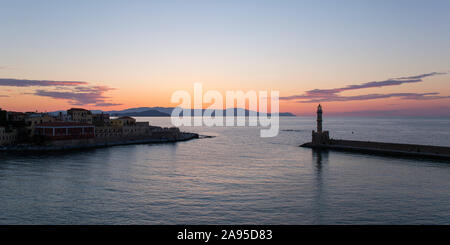 Chania, Kreta, Griechenland. Blick über den venezianischen Hafen in der Abenddämmerung, historischer Leuchtturm prominent. Stockfoto