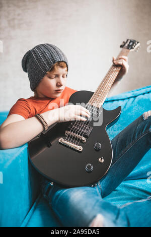 Rothaarige Junge spielt die Gitarre zu Hause - Rock Star Stockfoto