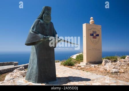 Preveli, Rethymno, Kreta, Griechenland. Kriegsdenkmal mit der Figur eines bewaffneten Mönchs in der Nähe des Oberen Preveli Klosters. Stockfoto