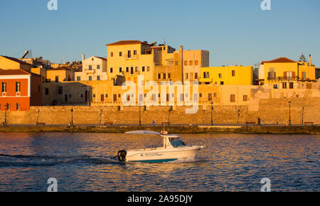 Chania, Kreta, Griechenland. Blick über den venezianischen Hafen bei Sonnenaufgang, kleines Boot auf dem Weg zum Meer. Stockfoto