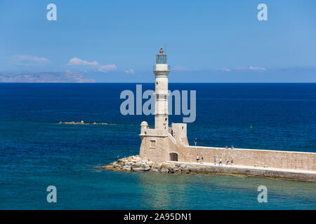 Chania, Kreta, Griechenland. Blick über den venezianischen Hafen auf den historischen Leuchtturm, Touristen sichtbar an der Meeresmauer. Stockfoto