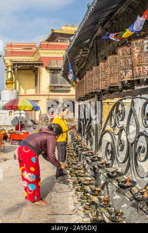 Zwei weiblichen buddhistischen Gläubigen beten und Beleuchtung Öllampen in den Swayambhunath Stupa Tempel, auch allgemein genannt Monkey Tempel, in Kathmandu. Stockfoto