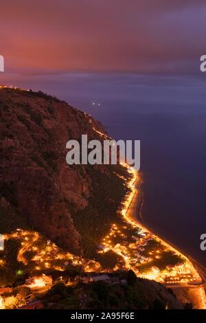 Night Shot, Blick auf den beleuchteten Ort Arco da Calheta an der Steilküste, Madeira, Portugal Stockfoto