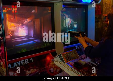 Person hält Gewehr ein computer spiel zu kontrollieren, arcade Anata kein Lager, Cyberpunk Stil, Kawasaki, Japan Stockfoto