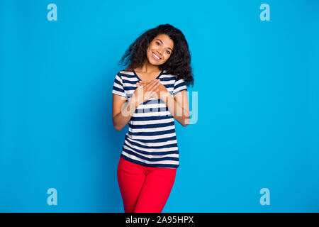 Portrait von fröhlichen Afro American Girl Hände Palmen auf der Brust fühlen Inhalt dankbar Tragen gut aussehende Outfit gestreiftes T-Shirt stilvoll trendy Stockfoto