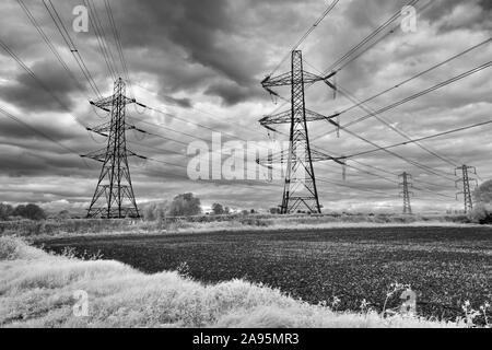 Schwarz und Weiß (Infrarot) Bild von Netz Strommasten unter einem wütenden Himmel in der Nähe von Cirencester Stockfoto