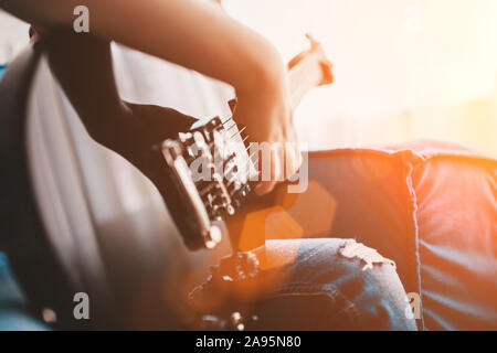 Nahaufnahme von einem Kind, das auf einem schwarzen E-Gitarre - die Hand schlägt die Saiten Stockfoto