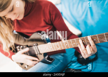 Mädchen mit blonden langen Haaren spielt Hard Rock auf einem schwarzen E-Gitarre Stockfoto