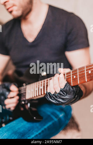 Rocker in schwarzen T-Shirts und Jeans spielen Hard Rock auf einem schwarzen E-Gitarre Stockfoto