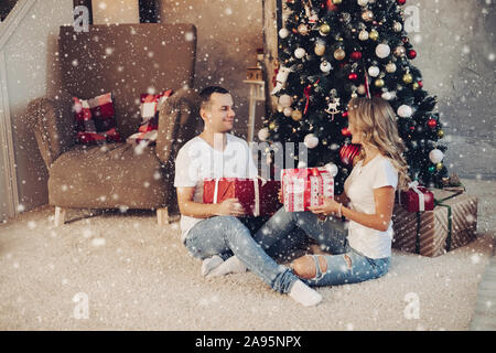 Paar mit Geschenken vor dem Weihnachtsbaum. Stockfoto