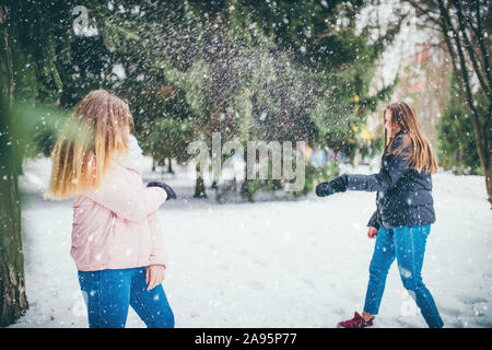 Auf einen guten Winter Tag, zwei Freunde spielen, Schneebälle auf einer Lichtung im Park zwischen den Bäumen Stockfoto