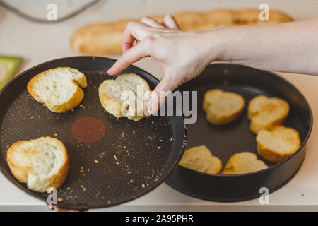 Frischen weißen Brot aus Weizen - in der Nähe der weiblichen Hände sind in einer Pfanne Stück Baguette für bruschetta Fried Stockfoto