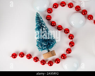 Ein kleines Spielzeug Weihnachtsbaum auf dem Hintergrund der transparente Kugeln, minimalistisch, Karte für das Neue Jahr und Weihnachten. Stockfoto