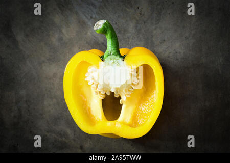 Gelbe Paprika in Scheiben geschnitten auf einem urigen Hintergrund mit einer Ansicht von oben. Capsicum Stockfoto