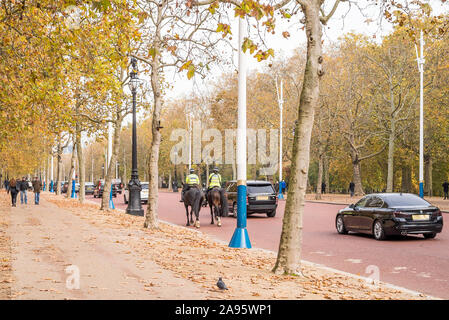 Rückansicht von zwei berittenen Polizisten, die im Herbst gemeinsam auf Pferden die Mall, London, Großbritannien, reiten. Stockfoto