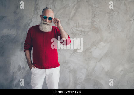 Portrait von trendige stilvolle wunderschöne alte Mann haben rote moderne Brücke weiße Hosen Hosen fühlen sich elegant auf Weihnachten grauer Beton isolierte Wand Stockfoto