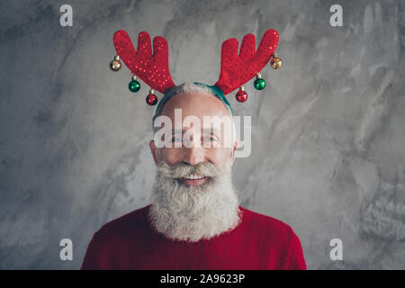 Portrait von positiven stilvolle alte Mann Hipster in deer Stirnband genießen Sie Weihnachten party x-mas Feier tragen Rot moderne Pullover über Grau isoliert Stockfoto