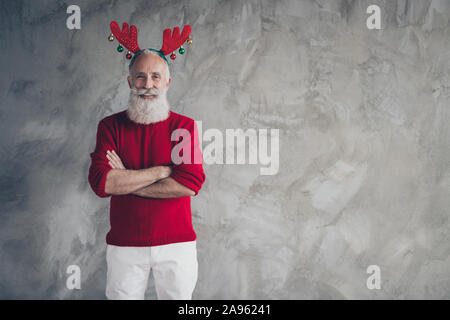 Portrait des modernen trendigen alter Mann in Red deer Hörner stirnband Cross Hands genießen Sie x-mas Party Weihnachten Feier tragen stilvolle Jumper weisse Hosen Stockfoto