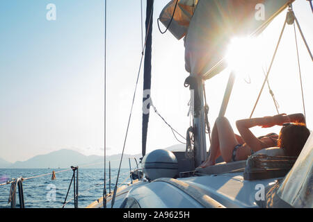 Bootsfahrt auf einer Yacht, eine junge Frau, Sonnenbaden an Deck eines Segelboot. Fragment des Decks. Stockfoto