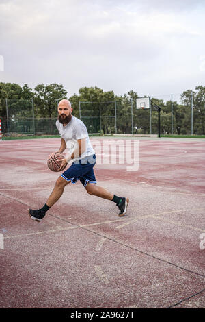 Junge Basketball Spieler läuft mit dem Ball auf einem alten Basketballplatz Stockfoto