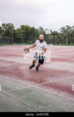 Junge Basketball Spieler läuft mit dem Ball auf einem alten Basketballplatz Stockfoto