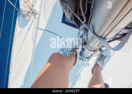 Kapitän eines Segelschiffes. Erklimmen Sie das Hubgerüst, die Fahrt einer Yacht, Yachting. Frauen Füße in weißen Turnschuhen auf den Stufen. Blick vom Mast. Stockfoto