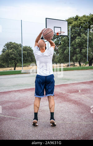 Die jungen Basketballer schießen ein Dreibettzimmer, auf einer Straße Basketballplatz Stockfoto