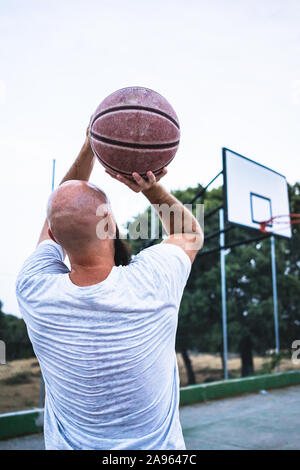 Die jungen Basketballer schießen ein Dreibettzimmer, auf einer Straße Basketballplatz Stockfoto