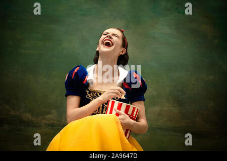 Junge Ballett Tänzerin als Schneewittchen Kino suchen oder an der Kamera mit Popcorn. Flexible Ballerina als Zeichen von fairytail in helle Kleidung. Moderne Geschichte im klassischen Märchen. Emotionen, Vergleich der Epochen. Stockfoto