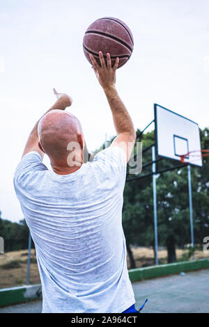 Die jungen Basketballer schießen ein Dreibettzimmer, auf einer Straße Basketballplatz Stockfoto