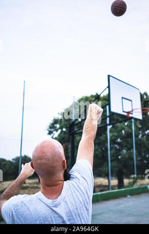 Die jungen Basketballer schießen ein Dreibettzimmer, auf einer Straße Basketballplatz Stockfoto