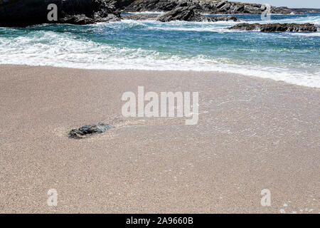 Wellen an den Strand. Einsame Stein im Sand in den Wellen Surf Zone. Stockfoto