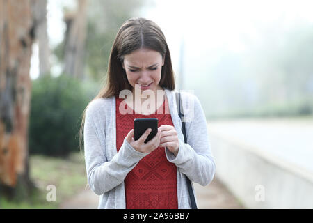 Vorderansicht portrait einer traurige Frau zu weinen über Handy in einem Park Stockfoto