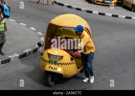 Ein Fahrer seine gelben Cocotaxi in einen Parkplatz in Havanna Altstadt (Habana Veija) in Kuba. Das Cocotaxi, ein vertrauter Anblick auf den Straßen o Stockfoto