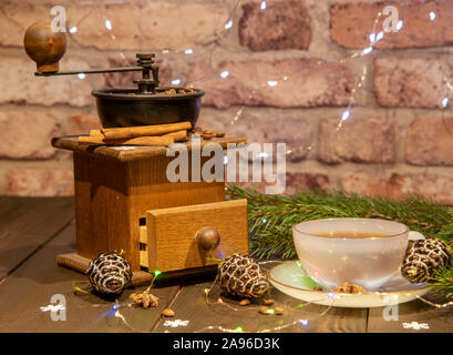 Eine alte manuelle Kaffeemühle und eine Porzellan Schale gegen eine Mauer. Neue Jahr im Loft-Stil. Stockfoto