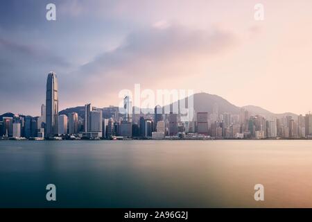 Moderne Stadt bei Sonnenuntergang. Victoria Harbour und die Skyline der Stadt mit Wolkenkratzern, Hong Kong. Stockfoto