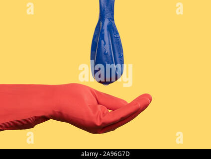 Red behandschuhte Hand unten blau Ballon mit Wassertropfen Hodenkrebs Stockfoto