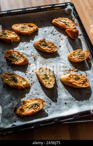 Knoblauch Parmesan Brotscheiben auf Backpapier Blatt mit Backblech. Frisch gebacken. Organisch gesunden Snacks. Stockfoto