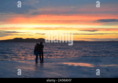 Unglaubliche Sonnenuntergang (Sonnenaufgang, Dämmerung) auf See mit Schattenrissen von Personen (Paar) in Zadar (Kroatien) Stockfoto