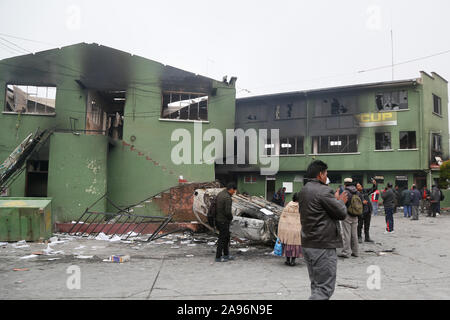 La Paz, Bolivien. 12 Nov, 2019. Volk eine ausgebrannte und über Auto klopfte neben einem zerstörten Polizeistation. Nach dem Rücktritt des bolivianischen Präsidenten Morales, marodierende Banden in dem südamerikanischen Land sind bis zu nicht gut - jetzt die Militärs wollen, dem Spuk ein Ende zu setzen. Credit: Gaston Brito/dpa/Alamy leben Nachrichten Stockfoto