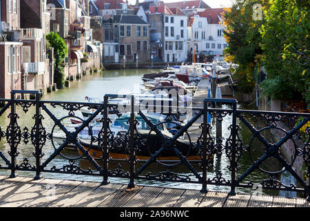 Nostalgie Blick durch einen gusseisernen Brücke Geländer auf einen Hafen und Gebäude in Dordrecht mit selektiven Fokus auf das Geländer Stockfoto