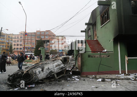 La Paz, Bolivien. 12 Nov, 2019. Volk eine ausgebrannte und über Auto klopfte neben einem zerstörten Polizeistation. Nach dem Rücktritt des bolivianischen Präsidenten Morales, marodierende Banden in dem südamerikanischen Land sind bis zu nicht gut - jetzt die Militärs wollen, dem Spuk ein Ende zu setzen. Credit: Gaston Brito/dpa/Alamy leben Nachrichten Stockfoto