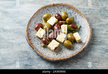 Grün und Kalamata Oliven, Kapern und Feta Käse auf rustikalen Holzmöbeln Hintergrund. Gesunde Snack Idee. Stockfoto
