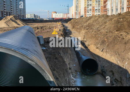 Der Prozess der Festlegung von Engineering- und Heizungssysteme. schwarzer Kunststoff Rohre werden in einem Graben. Stockfoto