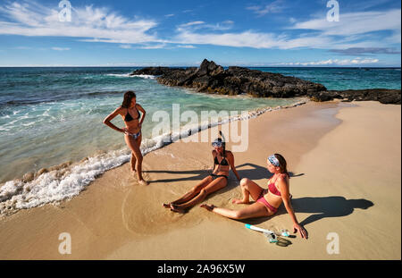 Drei Freunde genießen die Wellen und Sand auf Makalawena Strand, Hawaii Stockfoto