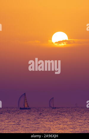 Drei Segelboote Adria mit der untergehenden Sonne und bunten Wolken im Hintergrund