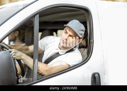 Lieferung Unternehmen Mitarbeiter in Uniform fahren weiß Cargo van Fahrzeug bei gleichzeitiger Bereitstellung von Ware an einen Kunden Stockfoto