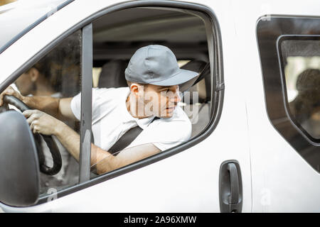 Lieferung Unternehmen Mitarbeiter in Uniform fahren weiß Cargo van Fahrzeug bei gleichzeitiger Bereitstellung von Ware an einen Kunden Stockfoto
