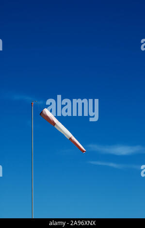 Rote und weiße Windsack auf einem metallpfosten auf blauen Himmel Hintergrund mit Zirruswolken Stockfoto